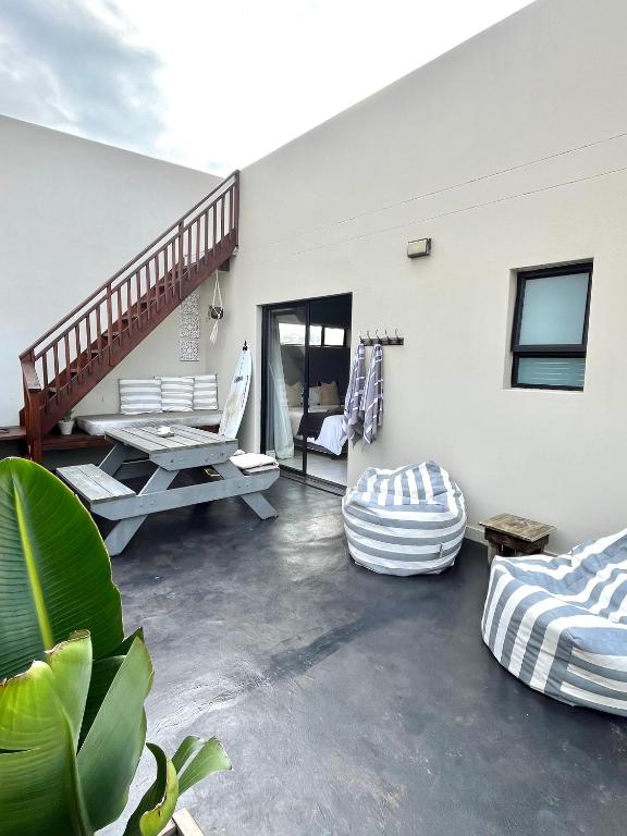a patio with a table and a bench and a staircase at Lower Point Surf Studio in Jeffreys Bay