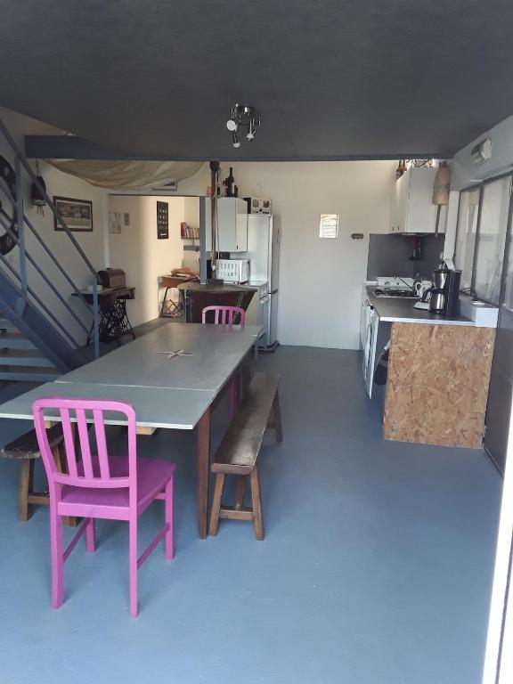 une cuisine avec une table et deux chaises roses dans l'établissement Ancienne maison de pêcheur pour un séjour reposant, à LʼAiguillon-sur-Mer