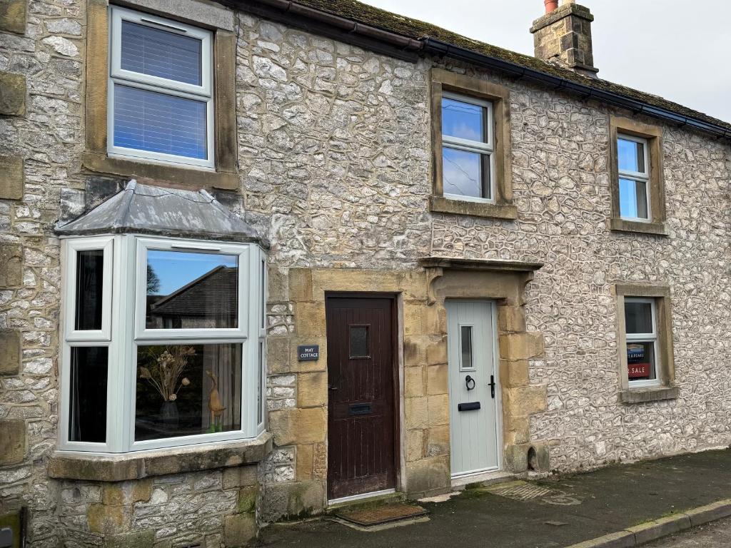 a stone house with white windows and a door at May Cottage in Tideswell