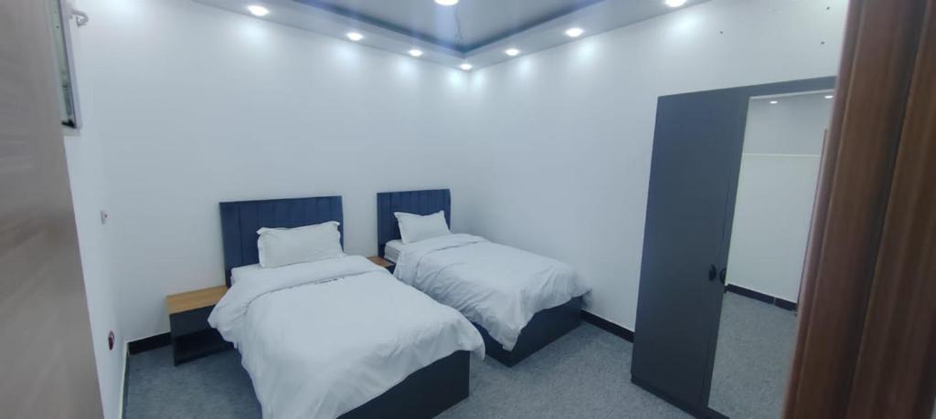 Motel beyza في السليمانية: سريرين في غرفة مع أضواء على الحائط