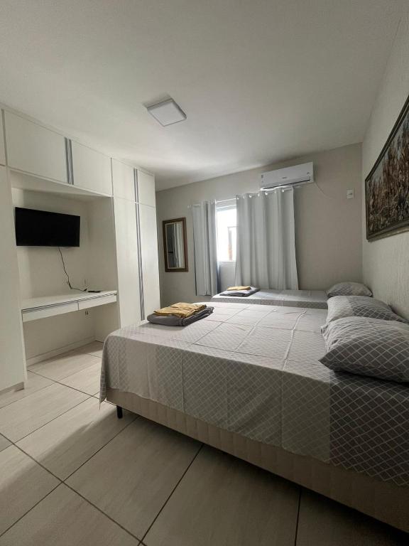 a bedroom with a large bed and a television at Pousada Bela Santa in Aparecida