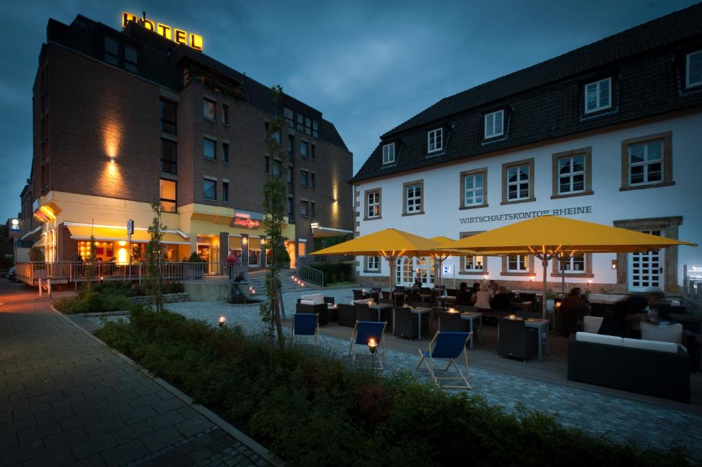 un patio del hotel con mesas, sillas y sombrillas en Hotel Lücke Rheine en Rheine