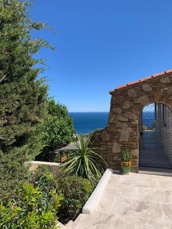 - un bâtiment en pierre avec une porte donnant sur l'océan en arrière-plan dans l'établissement Villa Les Mimosas, à Roquebrune-sur Argens