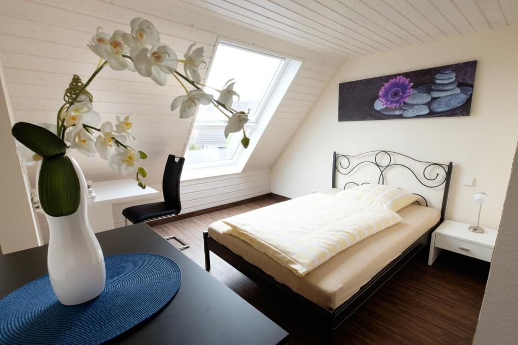 ein Schlafzimmer mit einem Bett und einer Vase mit Blumen auf dem Tisch in der Unterkunft Haus am Asang in Löwenstein