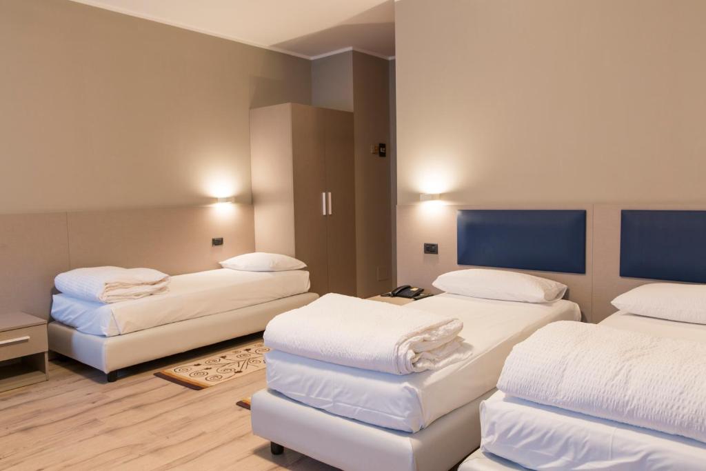 Habitación con 2 camas y sábanas blancas. en Albergo Montenegro en Maniago
