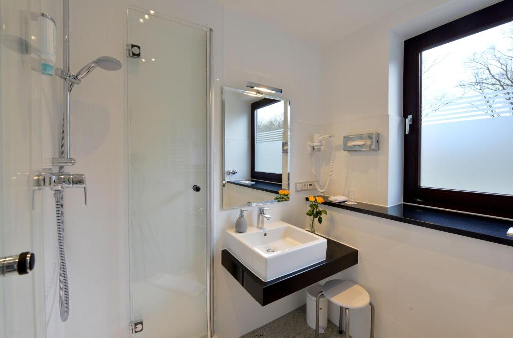a white bathroom with a sink and a shower at Hotel Spiegel in Cologne