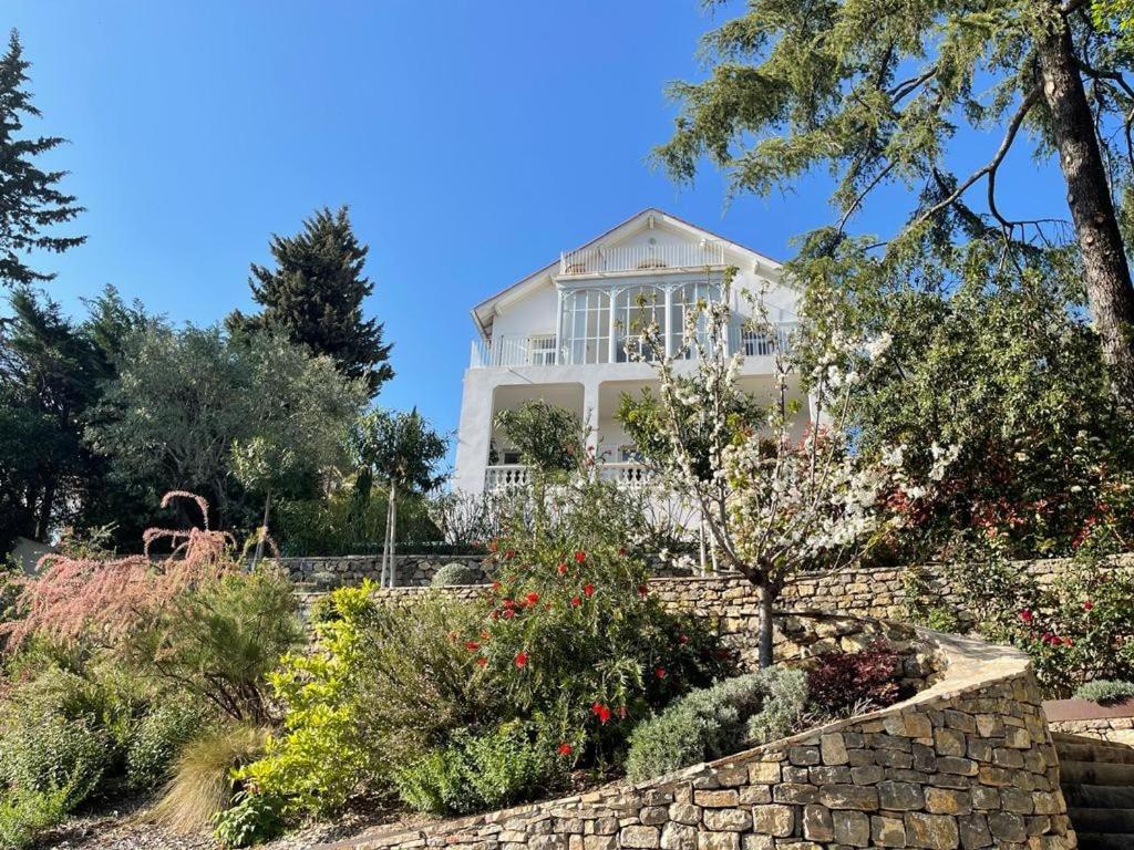 une maison blanche avec un mur en pierre et des arbres dans l'établissement Charming sea view villa with pool, à Hyères