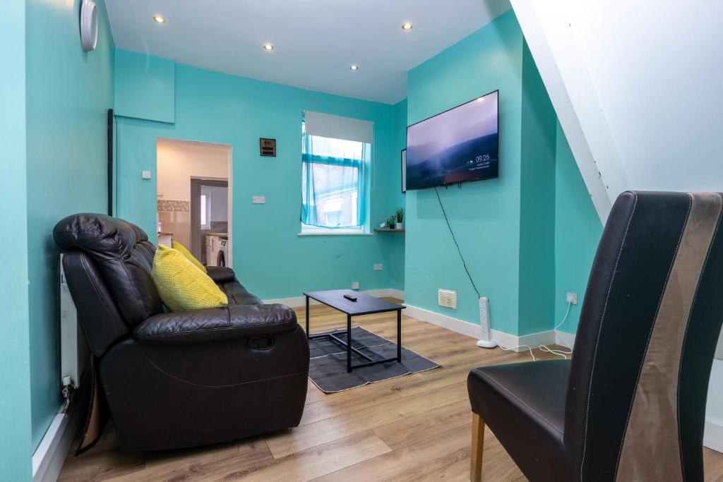a living room with a couch and a tv on a wall at 2Bed Mid Terrace Close To Station in Stoke on Trent