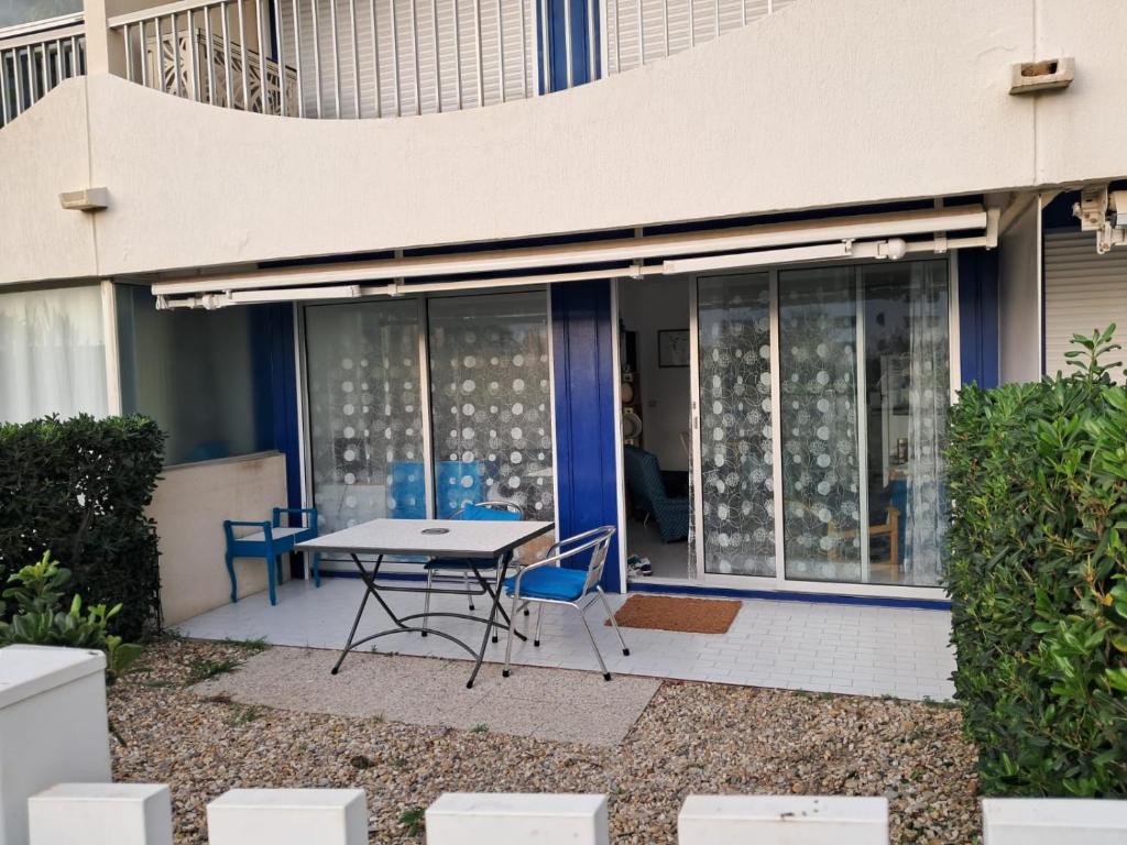 un patio avec une table et des chaises devant un bâtiment dans l'établissement Appartement à 1 minute de la mer, à La Grande Motte