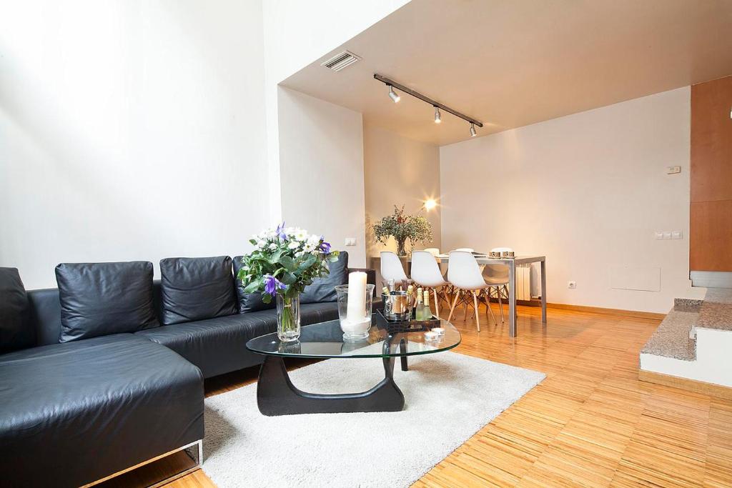 a living room with a black leather couch and a table at My Space Barcelona Park Güell Apartments in Barcelona