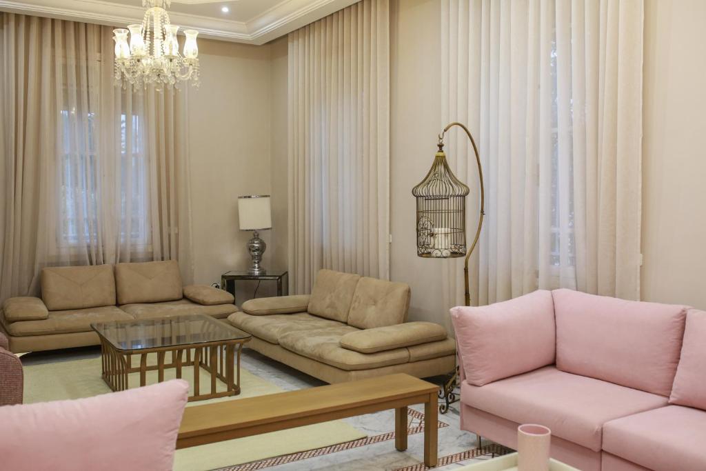 a living room with pink furniture and a chandelier at La maison française in Milletville