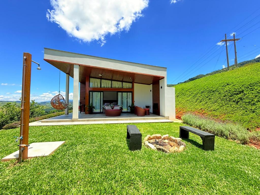 a small house on top of a grassy hill at Chalé Jacarandá - Vale do Baú in São Bento do Sapucaí