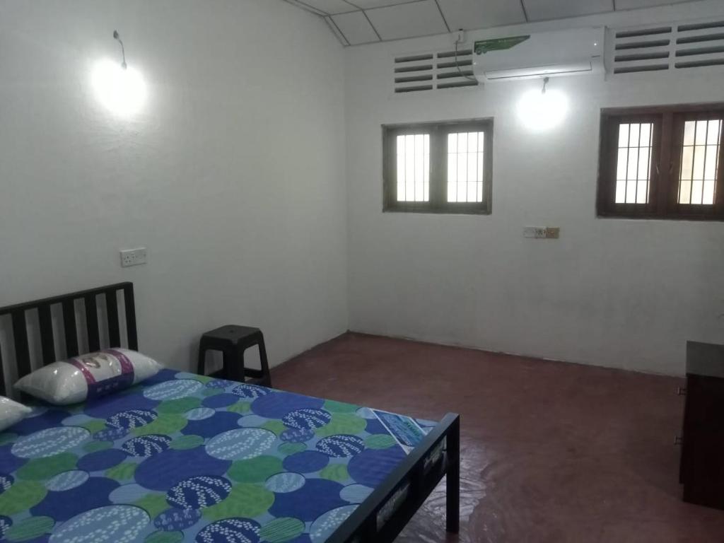 a bedroom with a bed in a room with windows at EECS Transit - Village stay in Katunayake