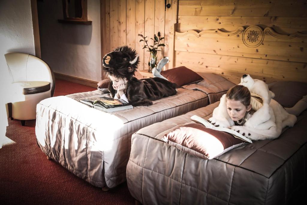 two beds with two dogs and a girl laying on them at Hôtel Le Refuge in Tignes