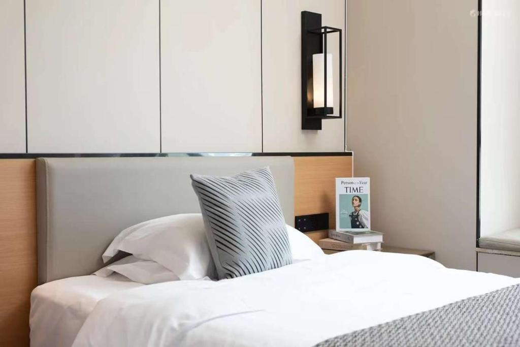 a bedroom with a white bed with white sheets at 宜尚酒店 日月广场骑楼老街店 in Haikou