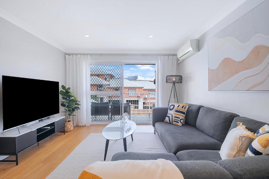 a living room with a couch and a flat screen tv at Greenslopes Cityview Haven in Brisbane