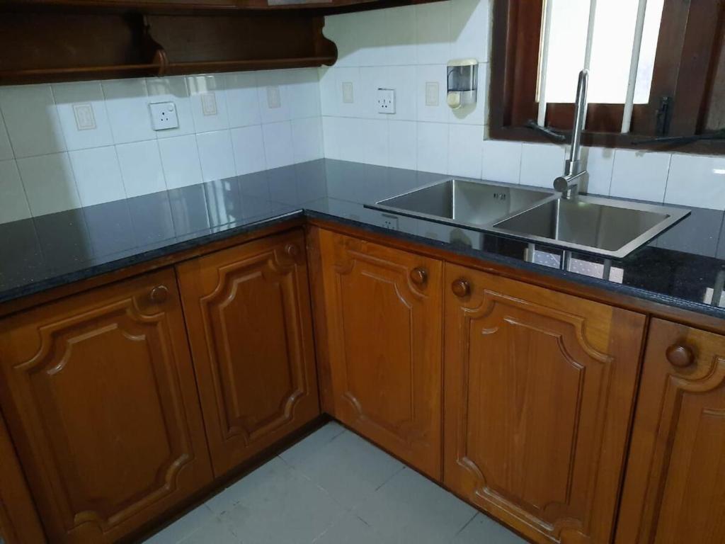 a kitchen with wooden cabinets and a sink at Heritage Bungalow Hikkaduwa in Hikkaduwa