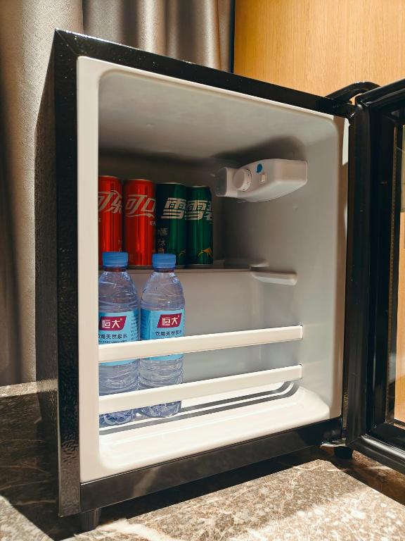 an open refrigerator filled with bottles of water at 宜尚酒店 日月广场骑楼老街店 in Haikou