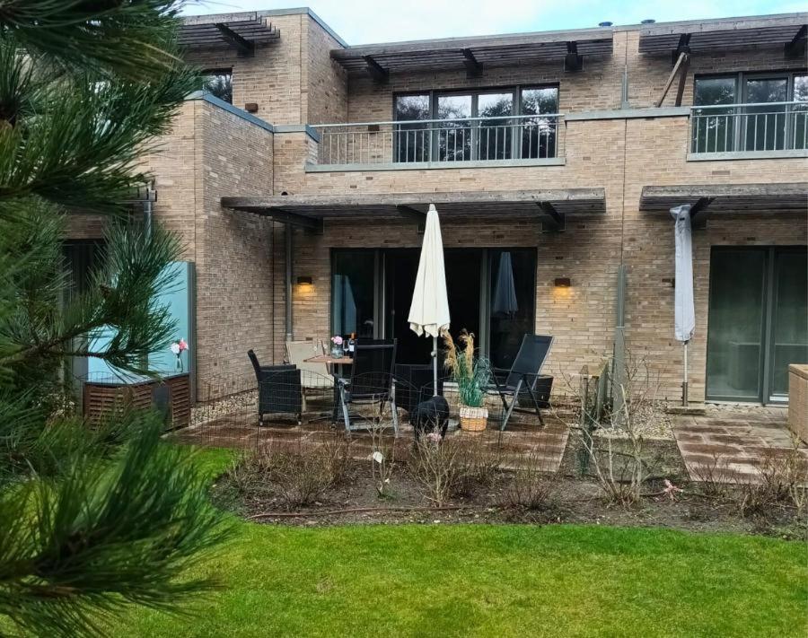 une maison avec un patio avec une table et un parasol dans l'établissement Residenz-Am-Wald-Nr-2-0, à Sankt Peter-Ording