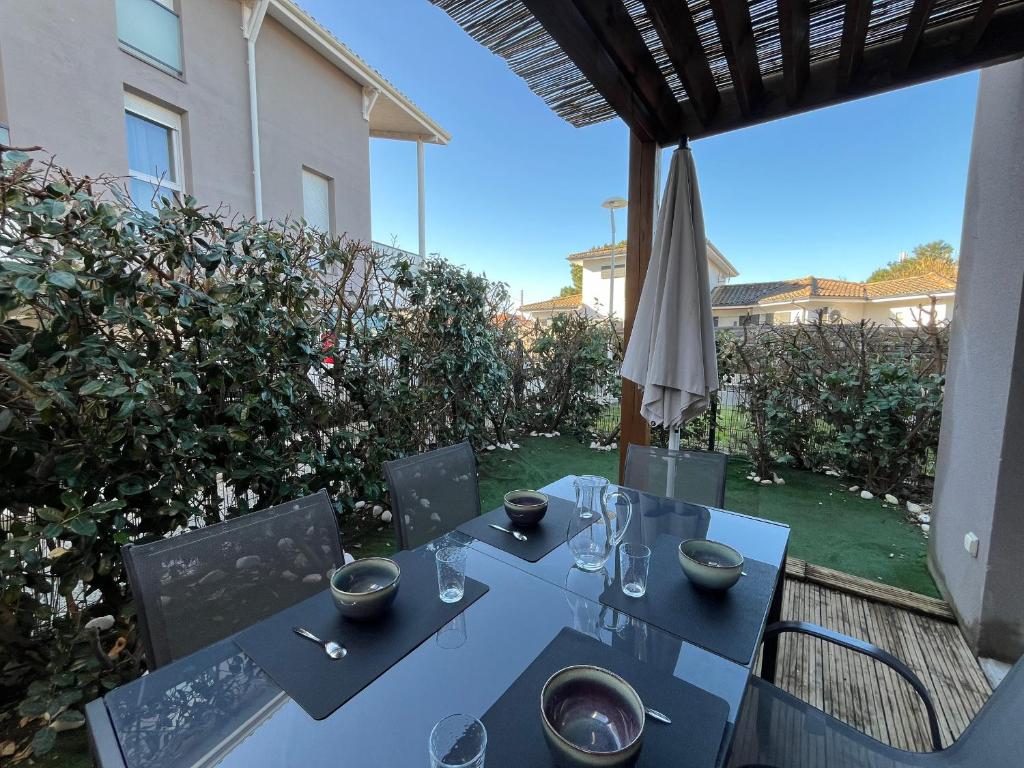 - une table et des chaises sur une terrasse avec un parasol dans l'établissement T3 Duplex La Teste, Terrasse, Parking Privé - FR-1-319-588, à La Teste-de-Buch