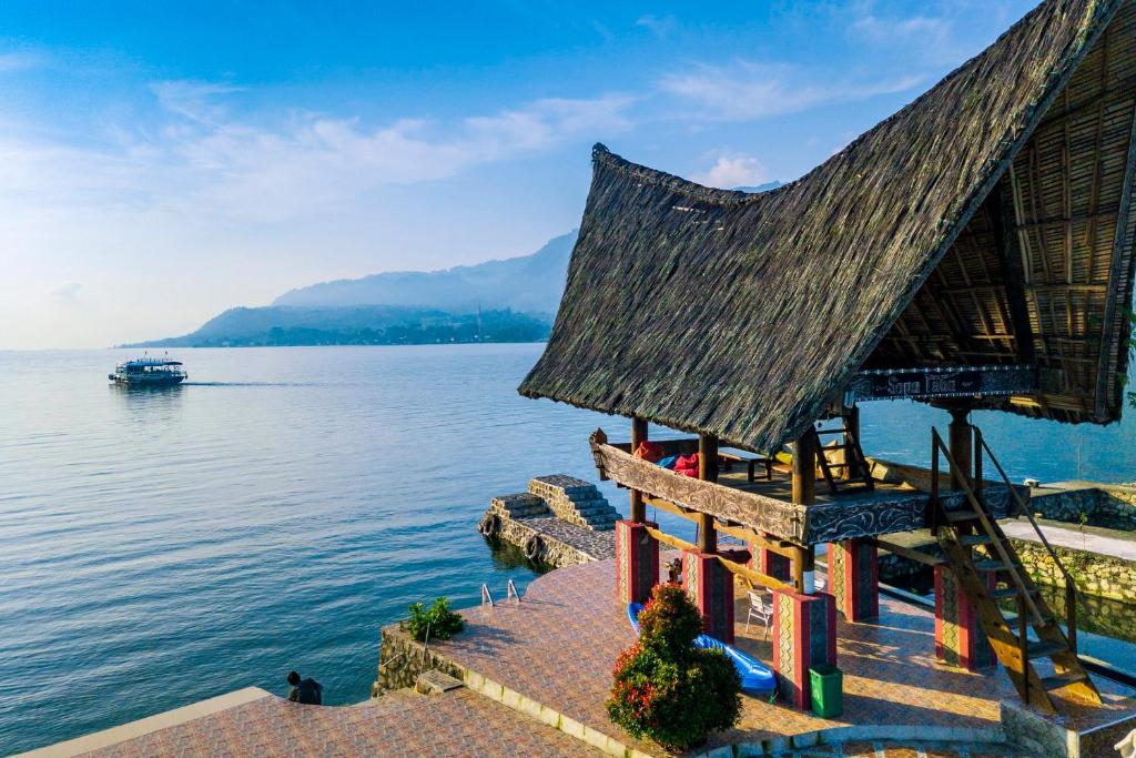 una casa a orillas de un lago con un barco en Tabo Cottages, en Tuk Tuk