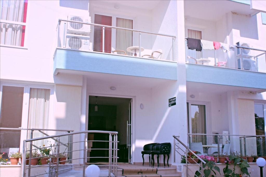 a white building with a balcony with chairs on it at Hotel Garden in Vlorë