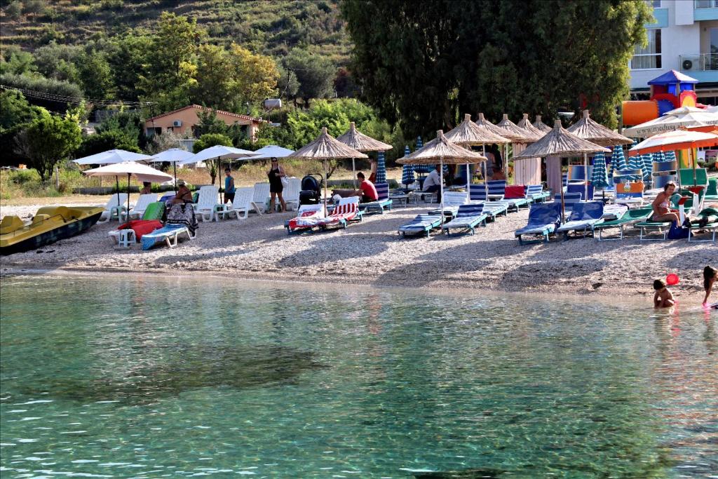 a beach with chairs and umbrellas and people in the water at Hotel Garden in Vlorë