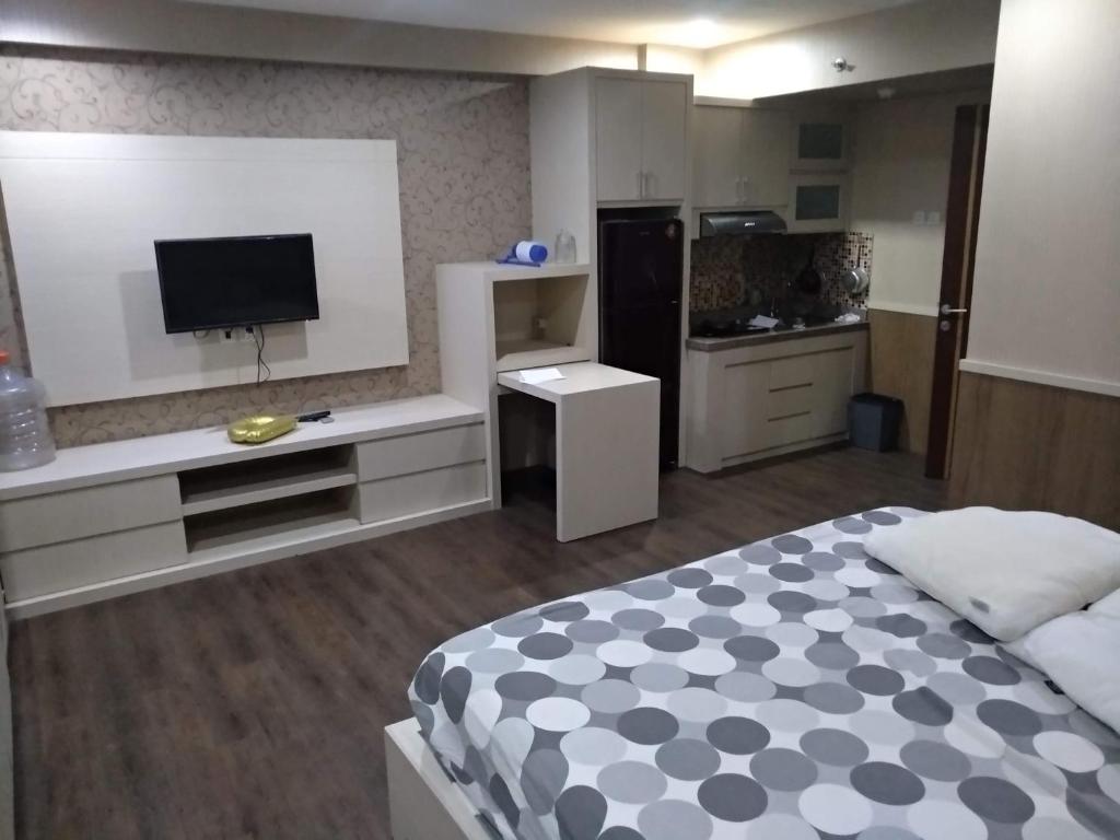 a bedroom with a bed and a tv and a kitchen at For rent or sale Puncak Kertajaya apartment in Surabaya