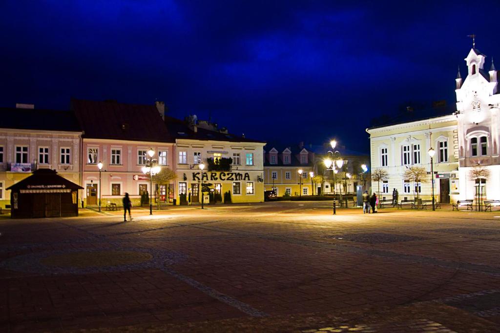 a town square at night with a building with a clock tower at Apartment Sweet Home Sanok in Sanok