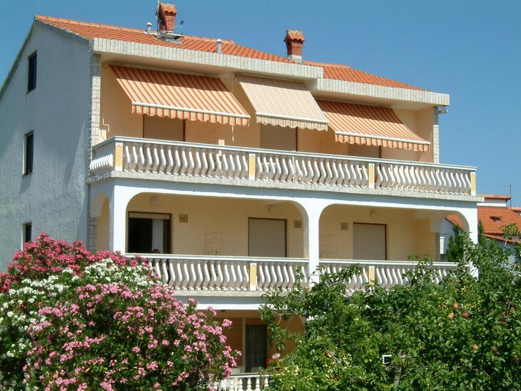 a large building with white balconies and pink flowers at Guesthouse Mira in Rab