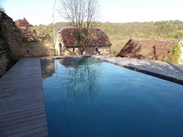 una grande piscina blu davanti a una casa di La maison lotoise d'Alice et Jeanne a Faycelles