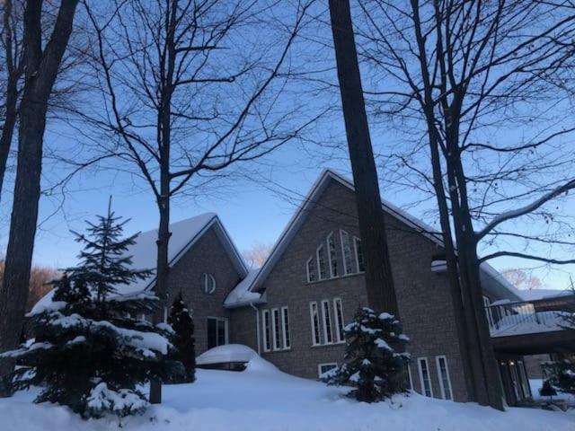 une grande maison en briques avec de la neige au sol dans l'établissement Cottage apartments at Lake Huron, à Midland