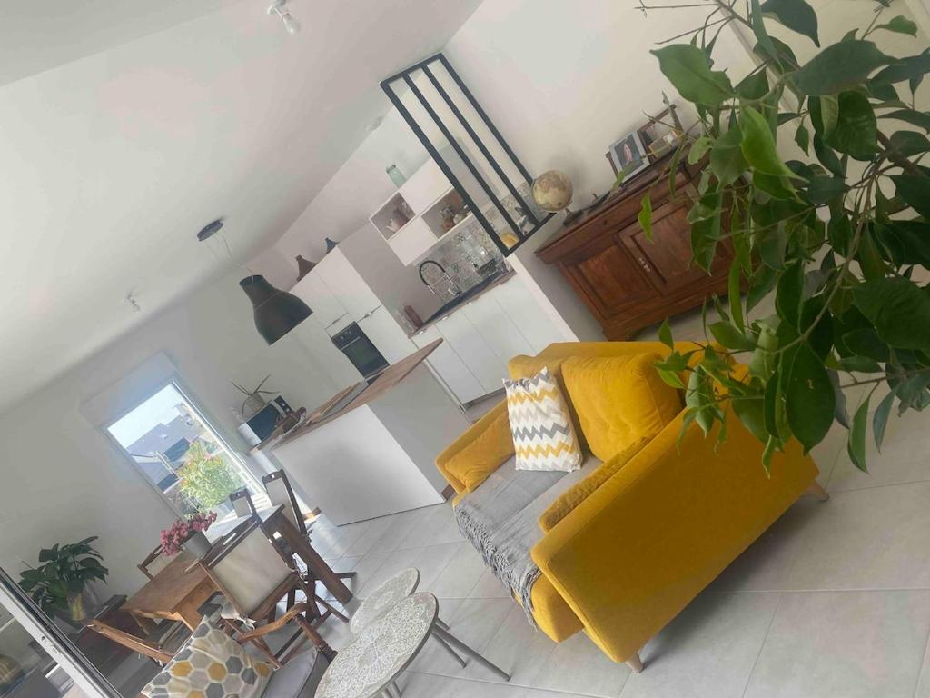 un salon avec un canapé jaune et une plante dans l'établissement Appartement spacieux et lumineux St Malo Paramé, à Saint-Malo