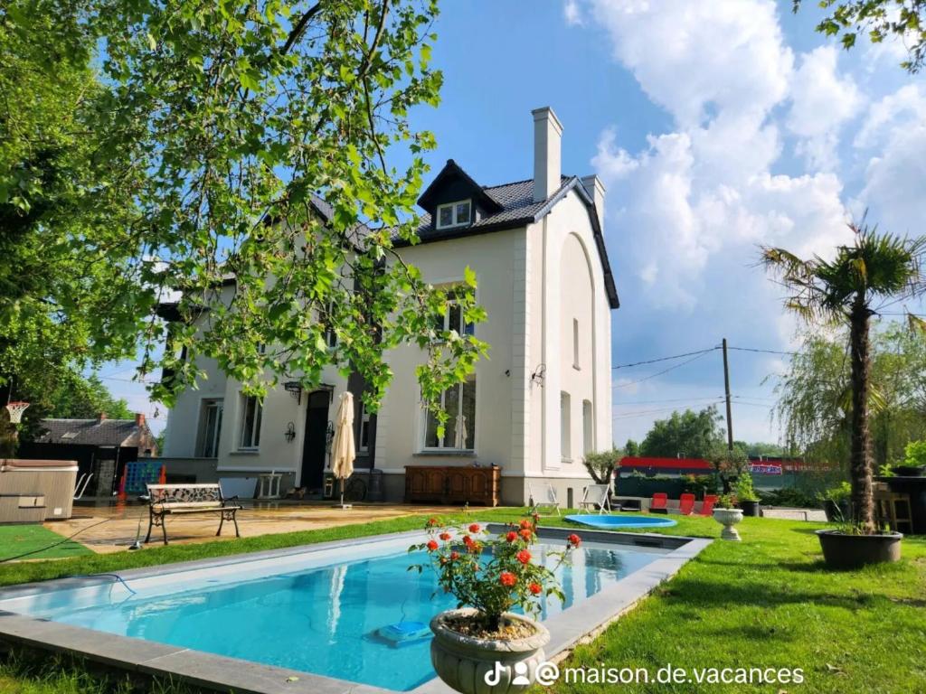 a house with a swimming pool and a church at maison de vacance in Feignies