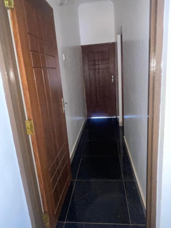 pasillo con 2 puertas de madera y suelo de baldosa en Home away from home, en Moshi