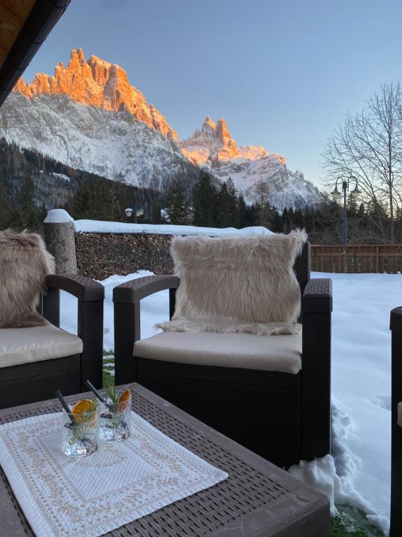 a table and chairs on a patio with snow covered mountains at Hotel Europa in San Martino di Castrozza