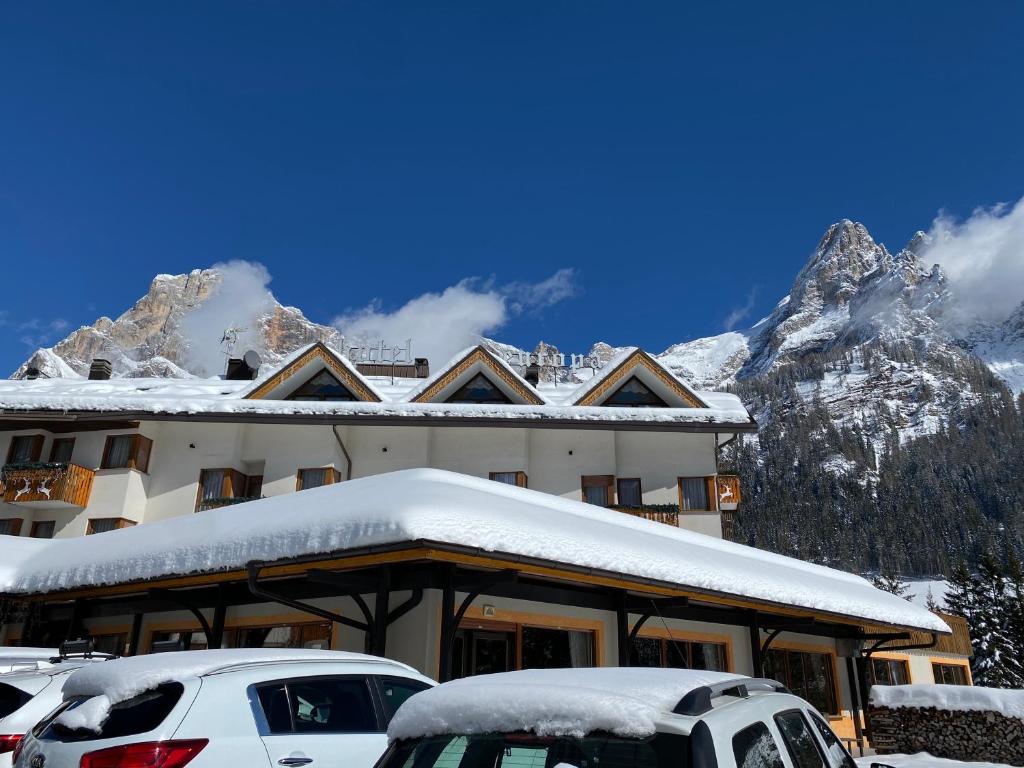 a snow covered building with cars parked in front of it at Hotel Europa in San Martino di Castrozza