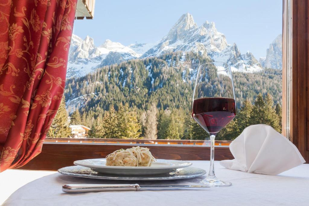 a table with a plate of food and a glass of wine at Hotel Europa in San Martino di Castrozza