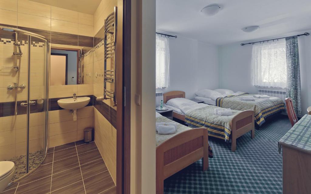 a room with two beds and a bathroom with a sink at Pensjonat Limba in Duszniki Zdrój