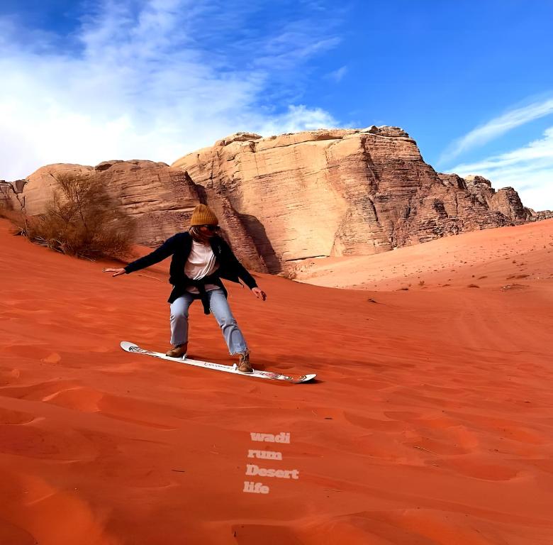 a person on a snowboard in the desert at wadi rum Desert life in Disah