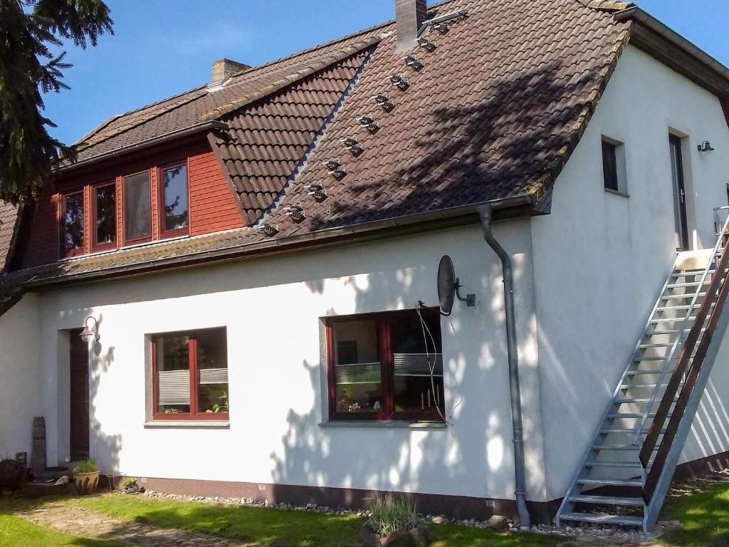 une maison blanche avec un toit marron dans l'établissement Ferienwohnungen am Waldrand, à Ahrenshagen