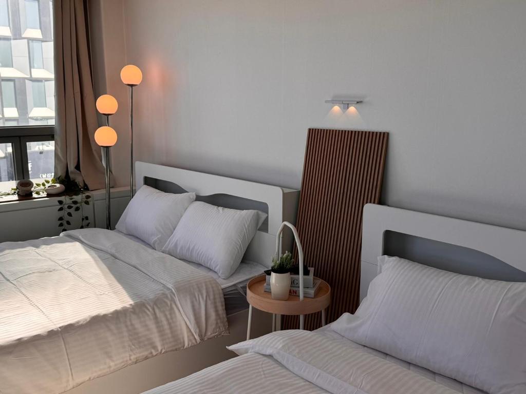 a bedroom with two beds and a table with a lamp at View-HongDae in Seoul