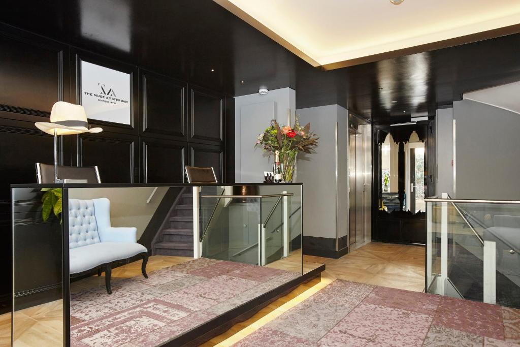 eine Lobby mit schwarzen Wänden, einem weißen Stuhl und Blumen in der Unterkunft The Muse Amsterdam - Boutique Hotel in Amsterdam