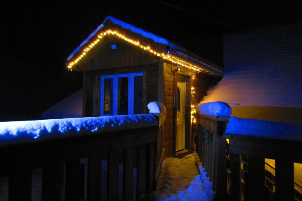 une maison avec des lumières au-dessus dans la neige dans l'établissement Gîte Les Fremi'Zh, à Saint-Maurice-sur-Moselle