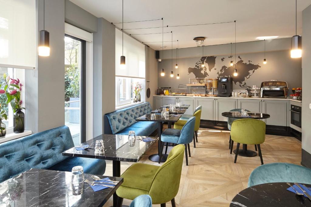a restaurant with tables and chairs and a kitchen at The Muse Amsterdam Hotel in Amsterdam