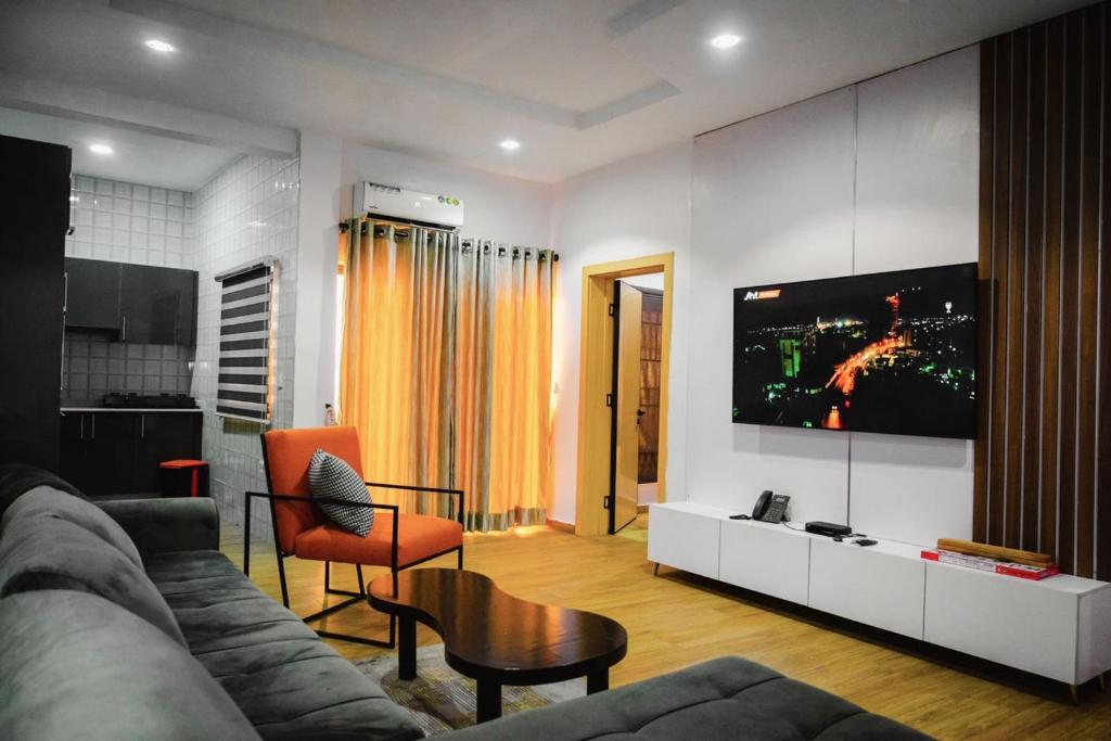 a living room with a couch and a tv on a wall at Shortlet spaces in Lekki