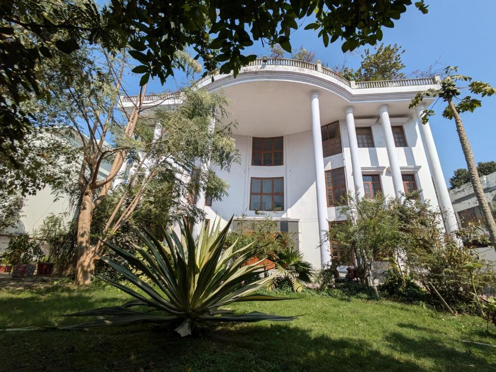 a white house with a palm tree in front of it at Mulberry Garden in Varanasi