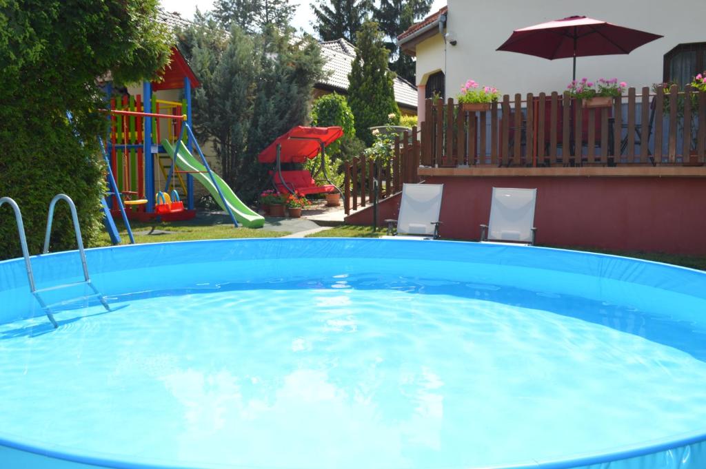 a large blue pool with a playground in a yard at Norbert Vendégház in Balatonszárszó