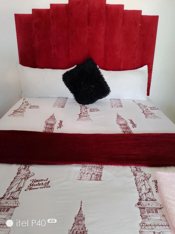 a bed with a red headboard with a black pillow at Tenders Accommodation Rooms Mafikeng in Mahikeng