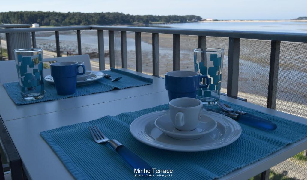 uma mesa com pratos e chávenas de café numa varanda em Minho Terrace em Caminha